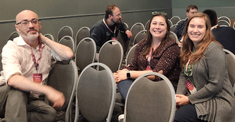 An image of people sitting in a conference room and smiling.