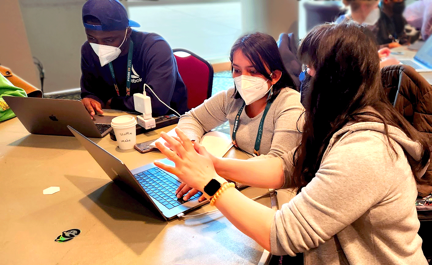 Image showing 3 people working at 2 computers during a spring at pyCon USA 2023.